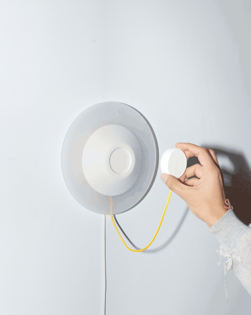 Touch Point Sconce with its magnetic puck on a yellow paracord tether